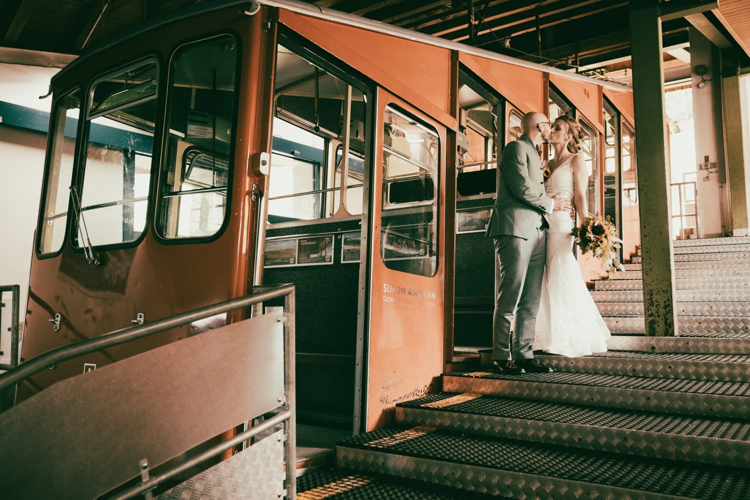 Brautpaar steigt Hand in Hand in eine nostalgische Seilbahn – romantischer Moment auf dem Weg zum Chäserrugg, fotografiert in Wildhaus, Toggenburg.