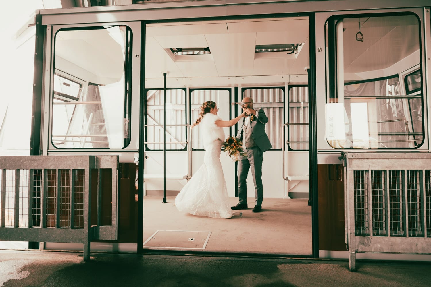 Braut und Bräutigam tanzen gemeinsam in einer nostalgischen Seilbahn – Hochzeit auf dem Chäserrugg, fotografiert von Adrian Flütsch.